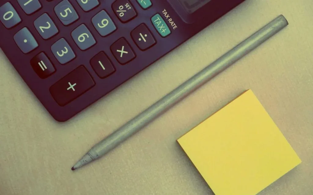 A calculator and notepad on a desk
