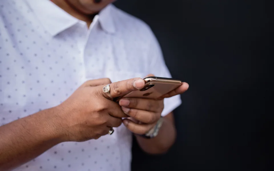 Holding a phone beside a cup of coffee